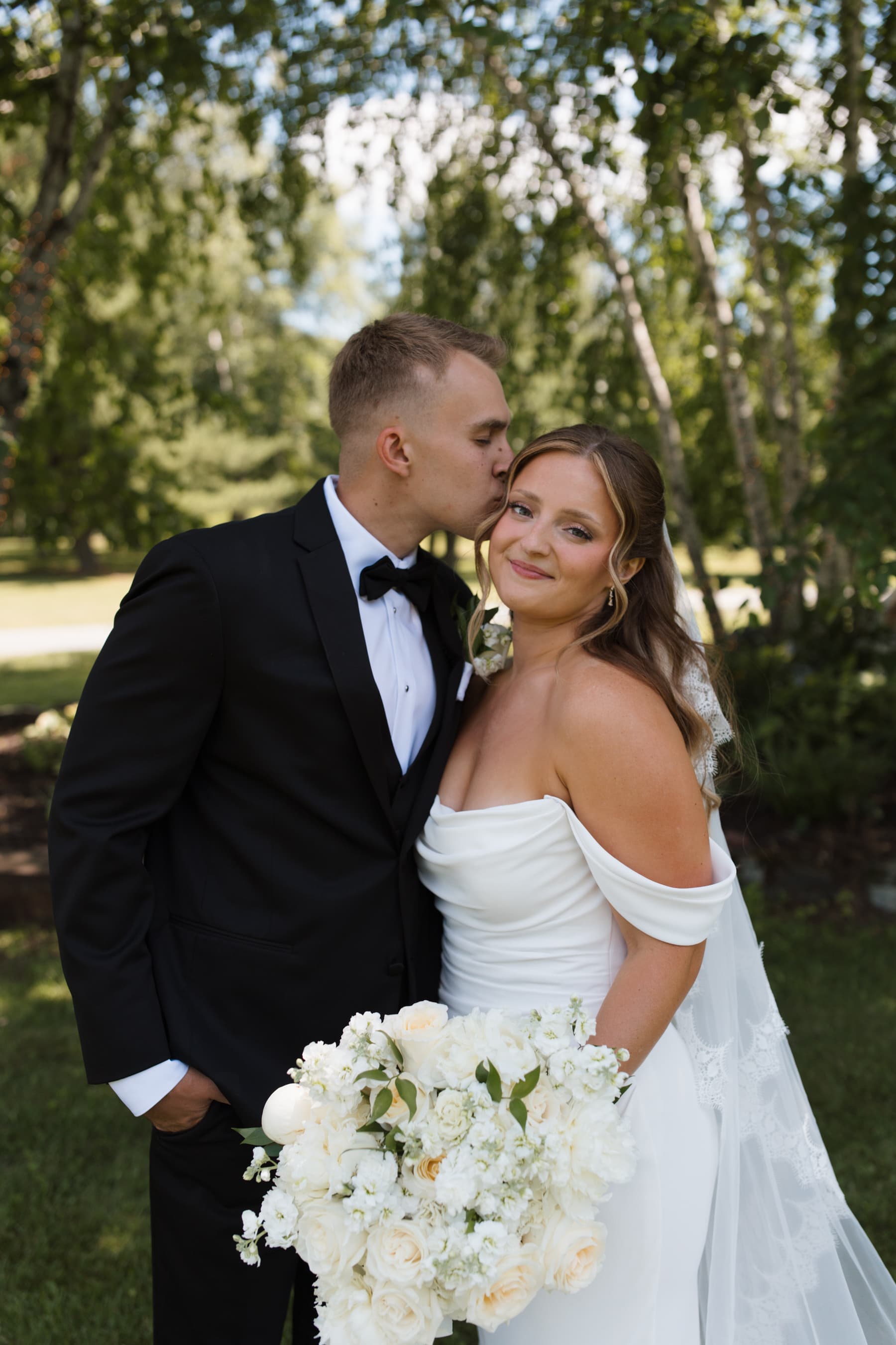 Groom embracing bride, holding a white bouquet