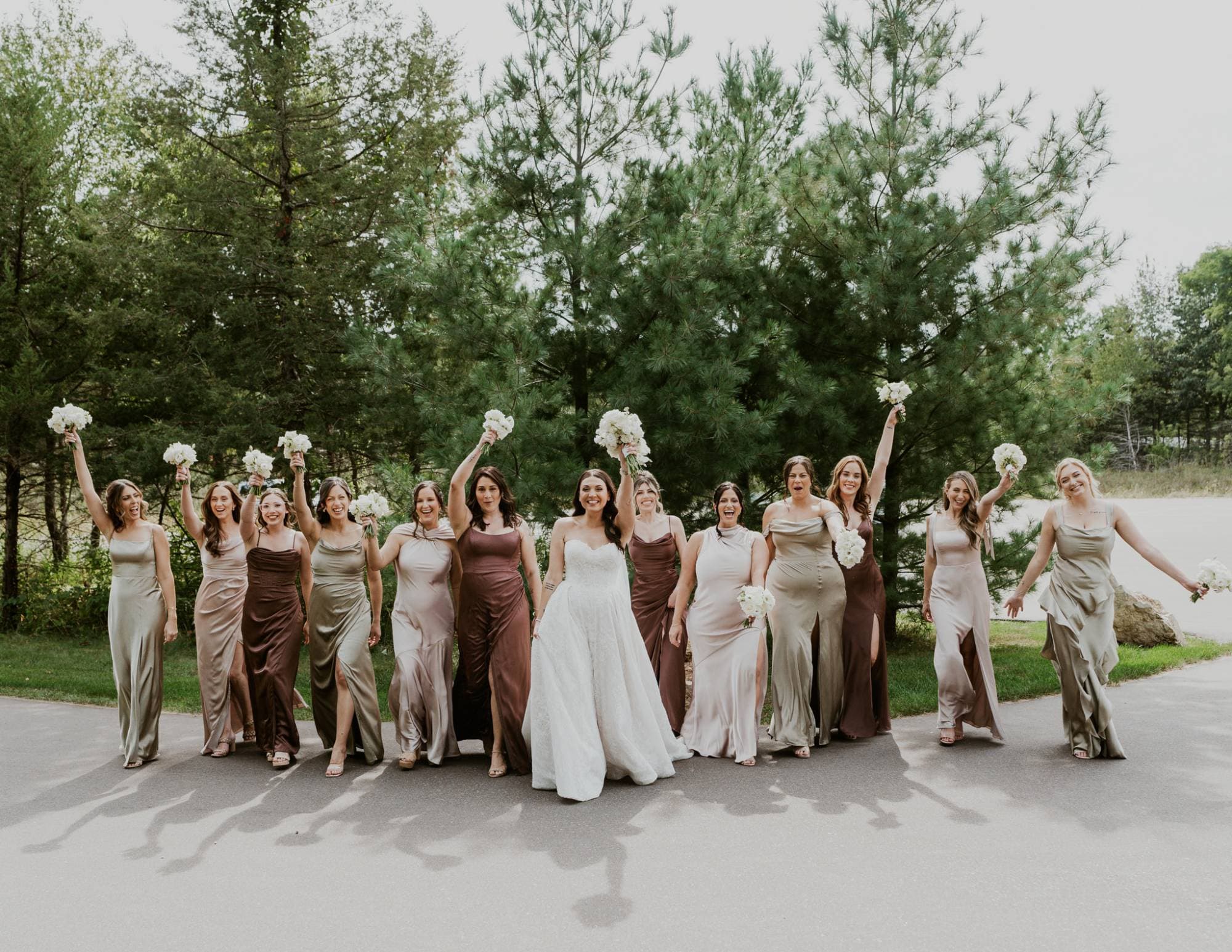 Bride and bridesmaids cheering with white bouquets raised