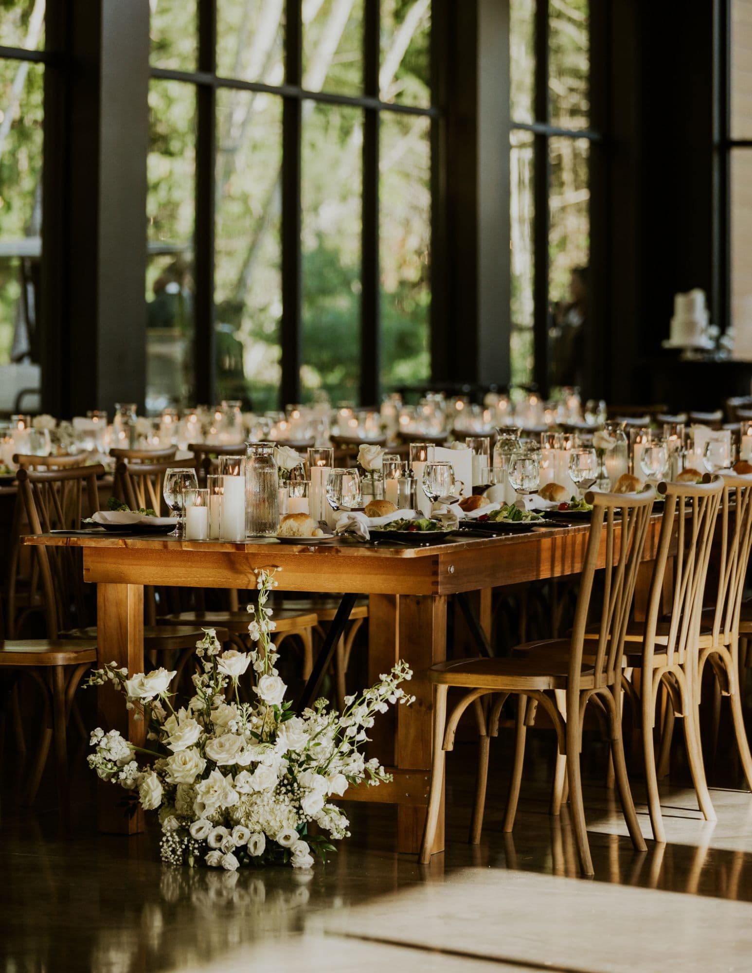Reception table with candles and a white floral arrangement on the floor