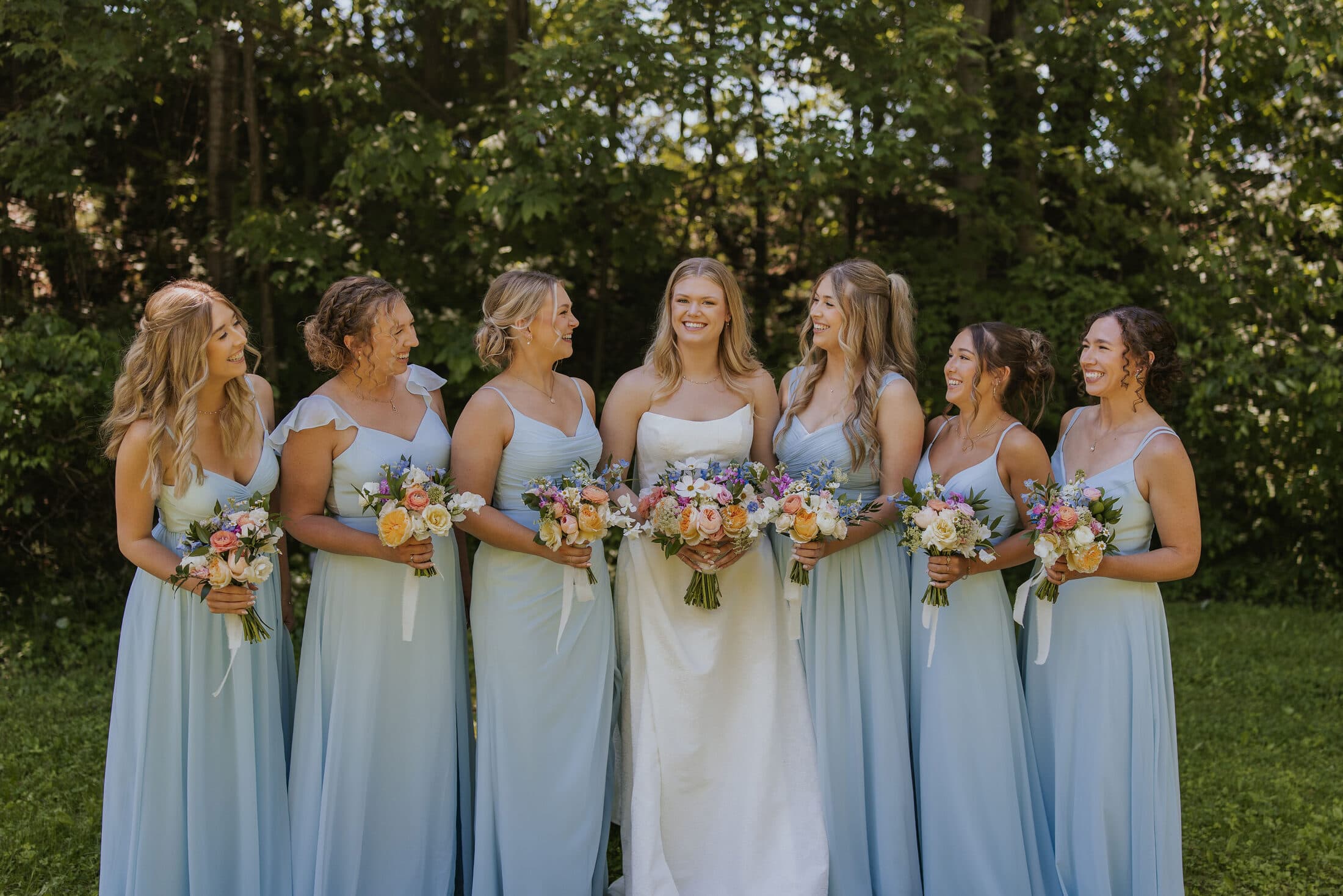 Bride surrounded by bridesmaids in dusty blue gowns